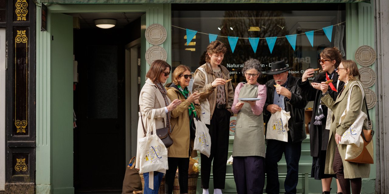 Group of 7 people outside a local greengrocer tasting some of the food