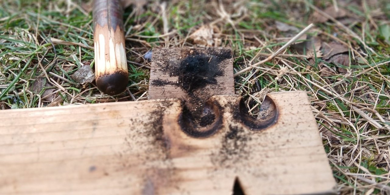 Two burn holes on a plank of wood 