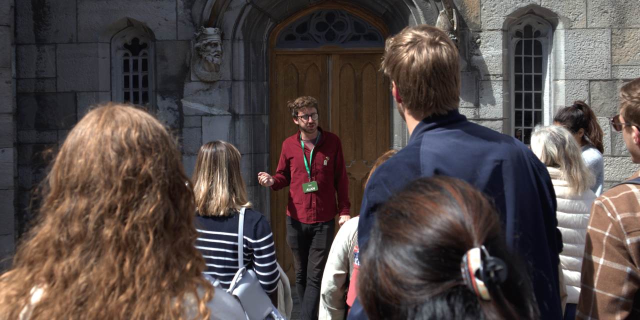 Tour guide wearing red jumper talking to crowd