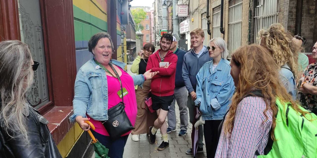 Tour guide speaking to group. Tour guide wearing bright pink top
