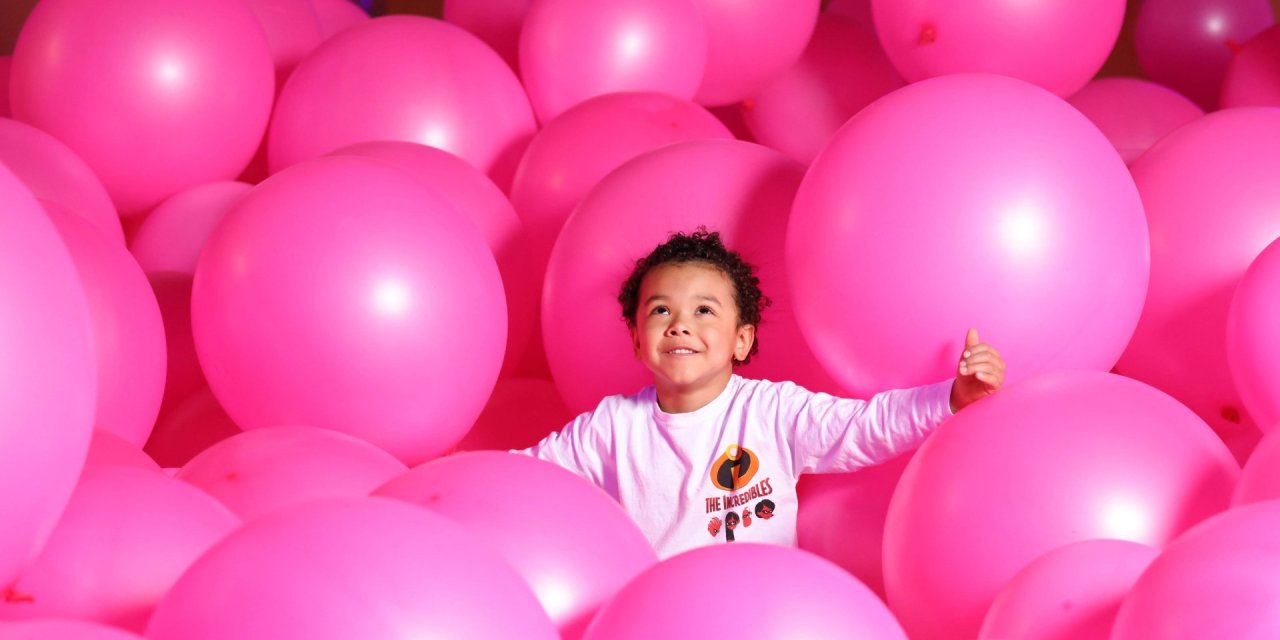 Young child playing surrounding by pink inflatables 